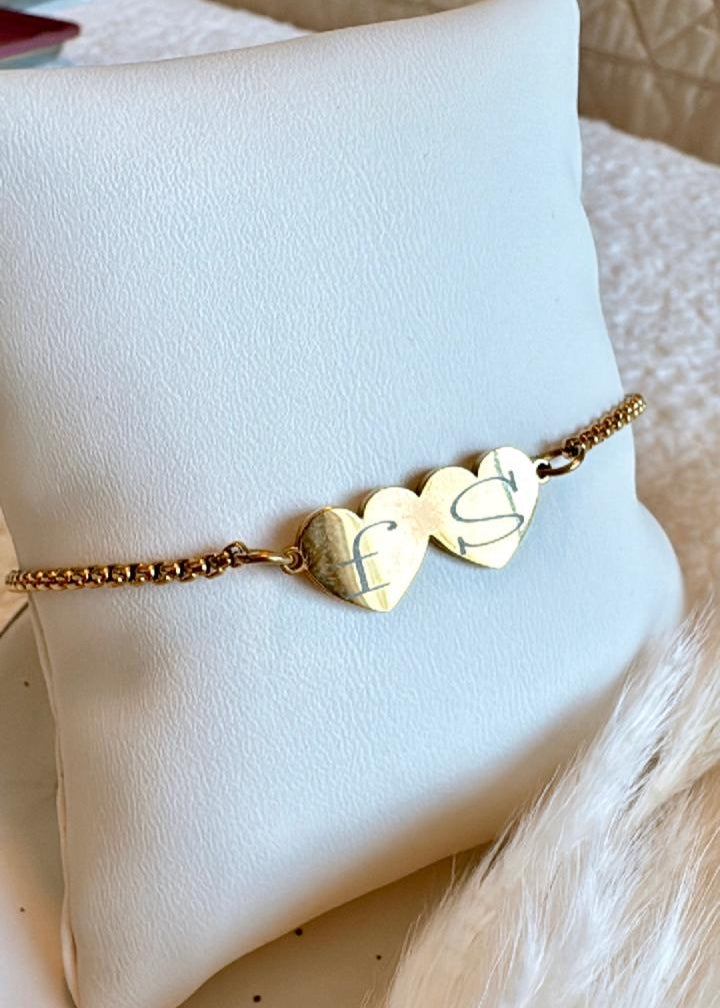 Gold bracelet with heart-shaped charms on a white cushion